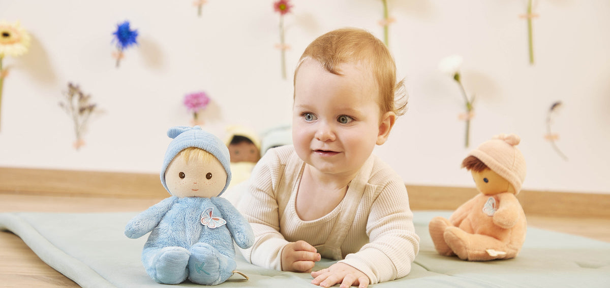 Baby on a play mat with Kaloo Tendre Bébé soft dolls
